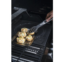 Champignons farcis sur une plaque de cuisson avec une pince à barbecue sur un gril