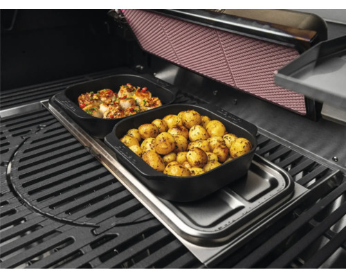 Barbecue avec des aliments dans des plats noirs : pommes de terre et fruits de mer.