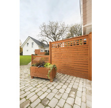 Holzzaun mit Pflanzkasten auf einer gepflasterten Terrasse vor einem Wohnhaus