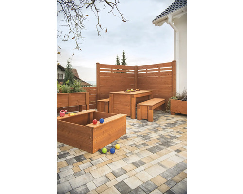 Scène de jardin avec clôture en bois, coin salon, bac à sable et jardinières