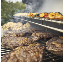 Viande et légumes sur un barbecue avec de la fumée.