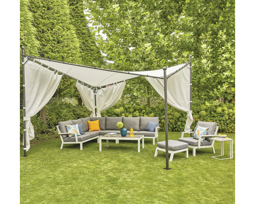 Salon de jardin sous un pavillon avec rideaux sur une pelouse.