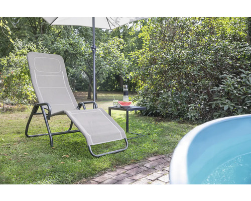 Gartenszene mit Liegestuhl, Sonnenschirm und Beistelltisch