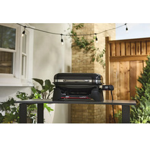 Barbecue électrique Weber Lumin sur une table dans le jardin.