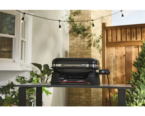 Barbecue électrique Weber Lumin sur une table dans le jardin.