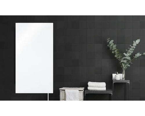 Salle de bains avec radiateur, panier et serviettes devant un mur carrelé