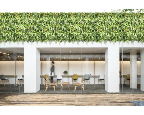 Immeuble de bureaux avec mur végétal artificiel, terrasse en bois et mobilier moderne.