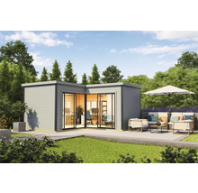 Bureau de jardin moderne avec façade en verre et terrasse avec coin salon dans un écrin de verdure.