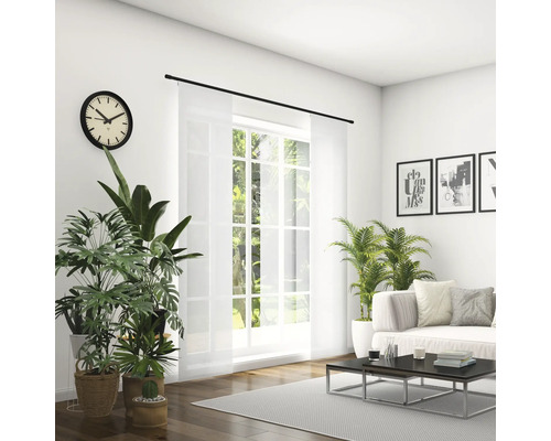 Salon lumineux avec canapé, table basse, plantes d''intérieur, horloge et rideau coulissant devant la fenêtre.