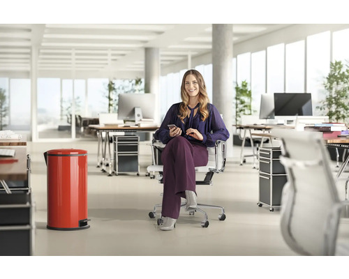 Scène de bureau avec une femme assise dans un fauteuil de bureau utilisant un téléphone portable et une poubelle à pédale rouge