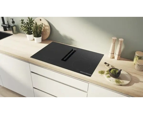 Plaque à induction noire avec hotte intégrée dans une cuisine claire.