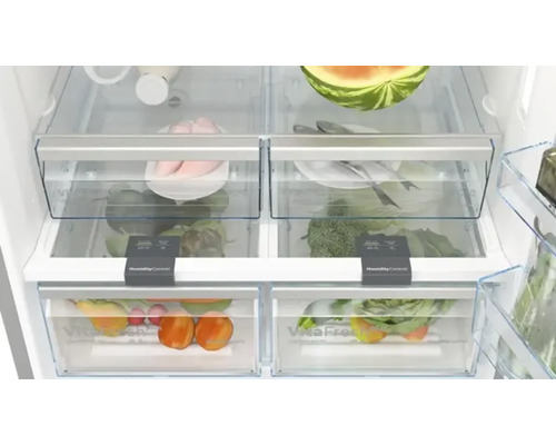 Innenansicht eines Kühlschranks mit Gemüse, Obst und Fleisch in transparenten Fächern.