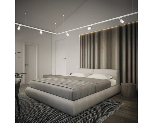 Chambre lumineuse avec lit double, lambris en bois et système de rail avec spots