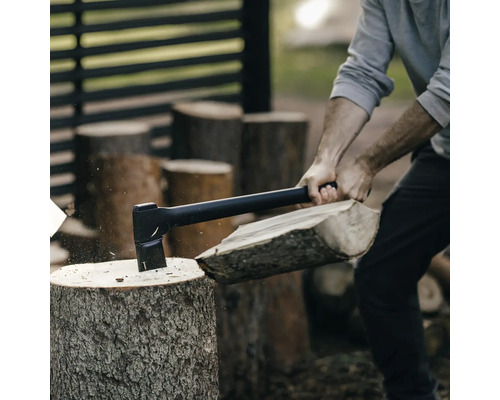 Eine Person spaltet mit einer Axt Holz.