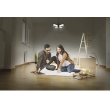 Couple planifiant une rénovation dans une pièce lumineuse avec une échelle et un plafonnier