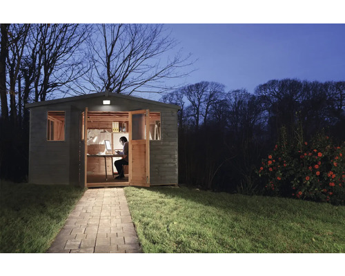 Gartenhaus bei Nacht mit Person am Schreibtisch