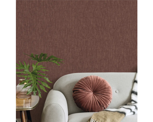 Wohnzimmer mit Textiltapete, Sofa, Kissen und Zimmerpflanze