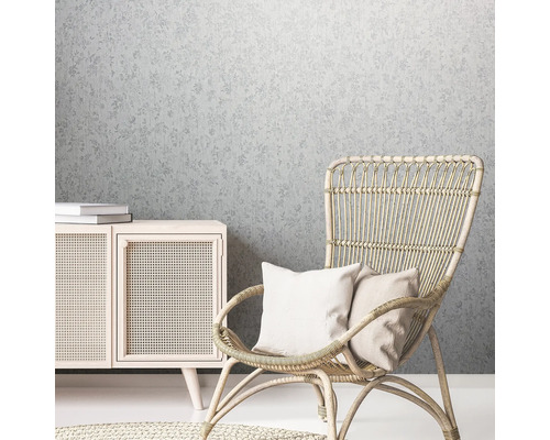 Dekoratives Wohnambiente mit floral gemusterter Tapete, Rattan Sessel und Holzkommode