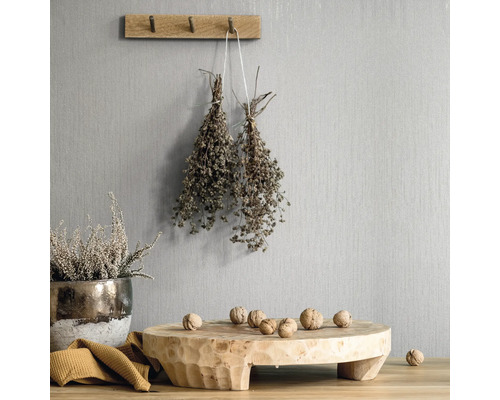 Scène décorative avec des éléments en bois, des herbes et des noix devant un mur texturé