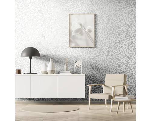 Salon avec papier peint en relief, commode, lampe, fauteuil et articles de décoration.