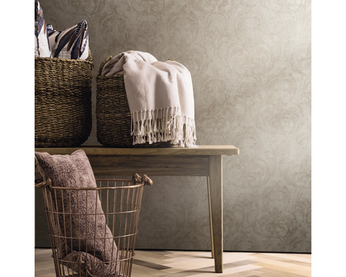 Paniers décoratifs et textiles sur une table en bois devant un papier peint à motifs