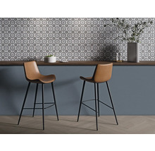 Deux tabourets de bar avec assises marron et structure noire devant un mur avec des carreaux à motifs.