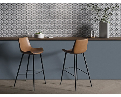 Deux tabourets de bar avec assises marron et structure noire devant un mur avec des carreaux à motifs.