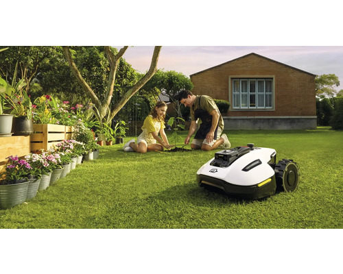 Szene im Garten mit einem Rasenmähroboter, einem Mann und einem Mädchen beim Pflanzen eines Baumes
