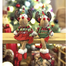 Deux figurines décoratives de rennes aux motifs de Noël sont assises sur une étagère devant un sapin de Noël.