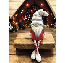 Nain de Noël avec jambes rayées sur fond en bois devant le sapin de Noël