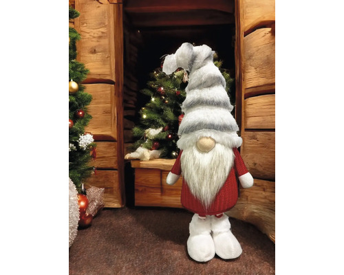 Weihnachtliche Dekoration mit einem Zwerg in roter Kleidung, weissem Bart und gestreifter Mütze neben einem Weihnachtsbaum.