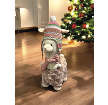 Figurine décorative de lama avec bonnet et écharpe à côté d''un sapin de Noël.