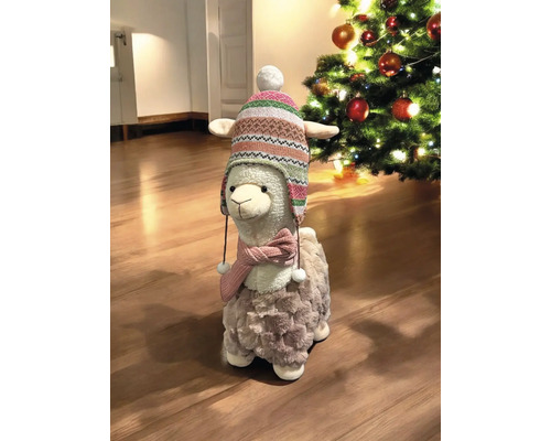 Figurine décorative de lama avec bonnet et écharpe à côté d''un sapin de Noël.