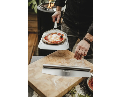 Scène avec pizza sur pelle à pizza, roulette à pizza et planche à découper