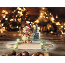Scène de Noël avec un bonhomme en pain d’épices, un arbre de Noël miniature et un rouleau à pâtisserie