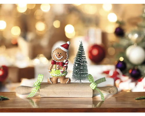 Dekorative Szene mit Lebkuchenmann, kleinem Weihnachtsbaum und Nudelholz auf einem Tisch