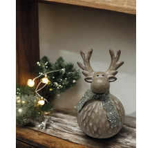Dekorativer Elch mit Schal auf einem Holzregal mit Weihnachtsbaum und Lichtern