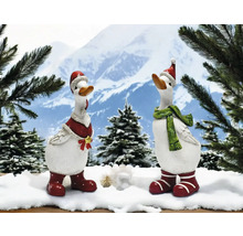 Zwei dekorative Gänsefiguren mit Weihnachtsmützen und Winteraccessoires vor Bergkulisse.