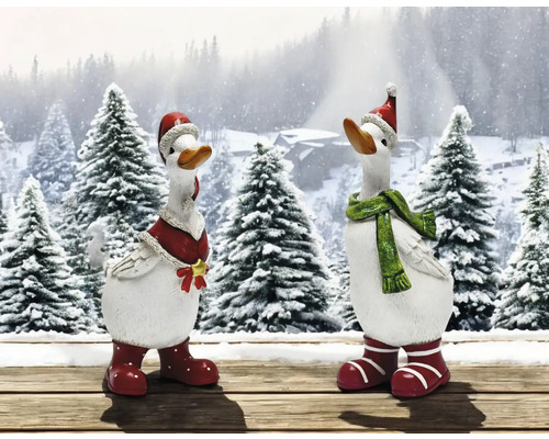 Zwei dekorative Gänsefiguren mit Weihnachtsmützen und Schals vor verschneiter Waldkulisse.