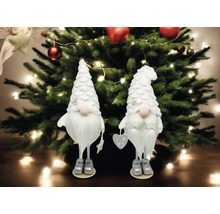 Deux figurines décoratives en forme de gnome devant un sapin de Noël avec des lumières et des décorations.
