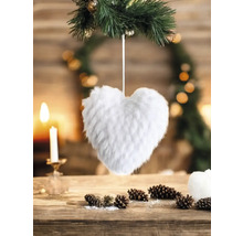 Cœur décoratif en fausse fourrure sur branche de sapin, décoration de table avec bougie et pommes de pin.