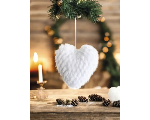 Dekoratives Herz aus Kunstfell an Tannenzweig, Tischdeko mit Kerze und Tannenzapfen.