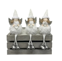Trois figurines d''anges de Noël sont assises sur une caisse en bois grise, décoration de Noël