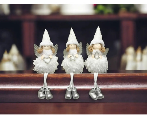 Drei dekorative Engel mit Flügeln und Zipfelmützen sitzen auf einem Regal