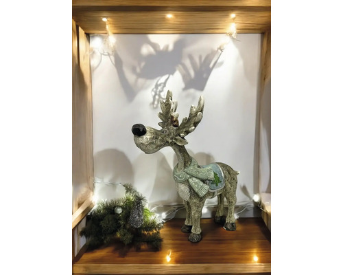Renne décoratif avec écharpe sur une étagère avec sapin de Noël et lumières
