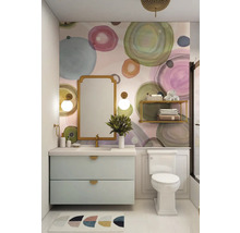 Salle de bains lumineuse avec meuble sous-lavabo, miroir et toilettes devant un mur à motif circulaire