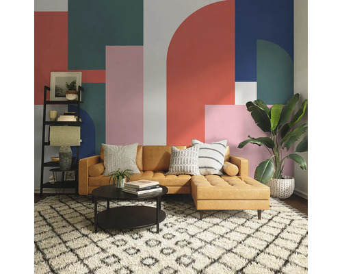 Salon avec canapé marron, table basse, étagère et plante d''intérieur devant un mur à motifs géométriques