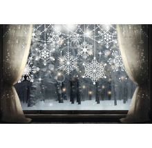 Winterfenster mit Schneeflockenaufklebern und Blick auf verschneiten Wald