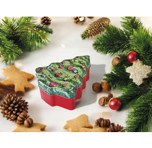 Weihnachtliche Szene mit Guetzli, Tannenzweigen, Nüssen und einer Dose in Tannenbaumform.