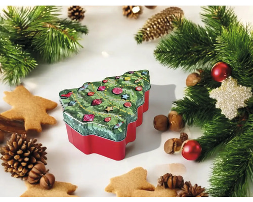 Weihnachtliche Szene mit Guetzli, Tannenzweigen, Nüssen und einer Dose in Tannenbaumform.